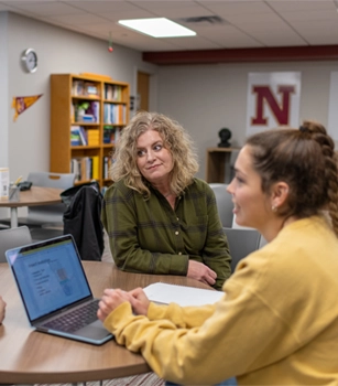 Student with laptop getting help from a staff