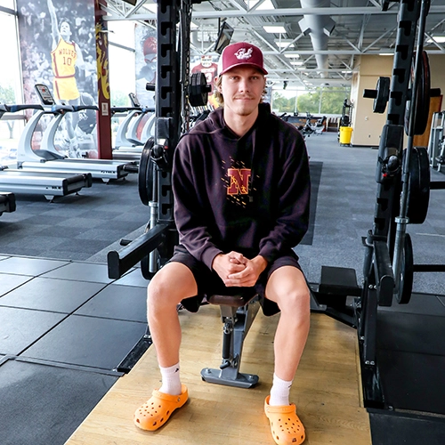 Male student sitting on exercise equipment 